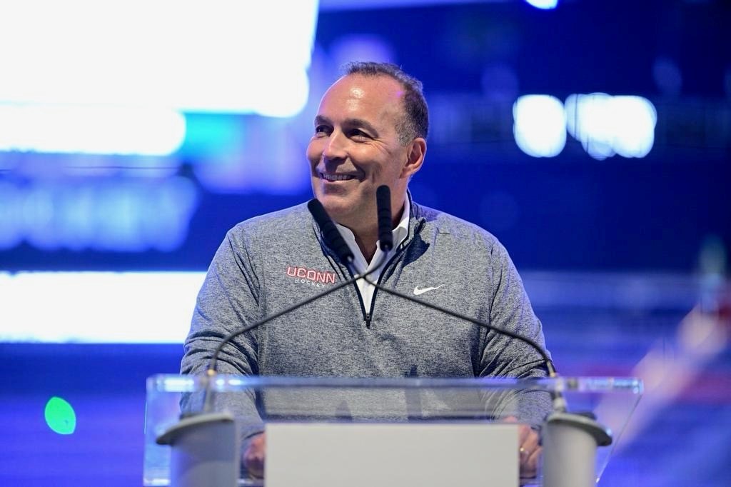 Dan Toscano in front of a podium smiling.