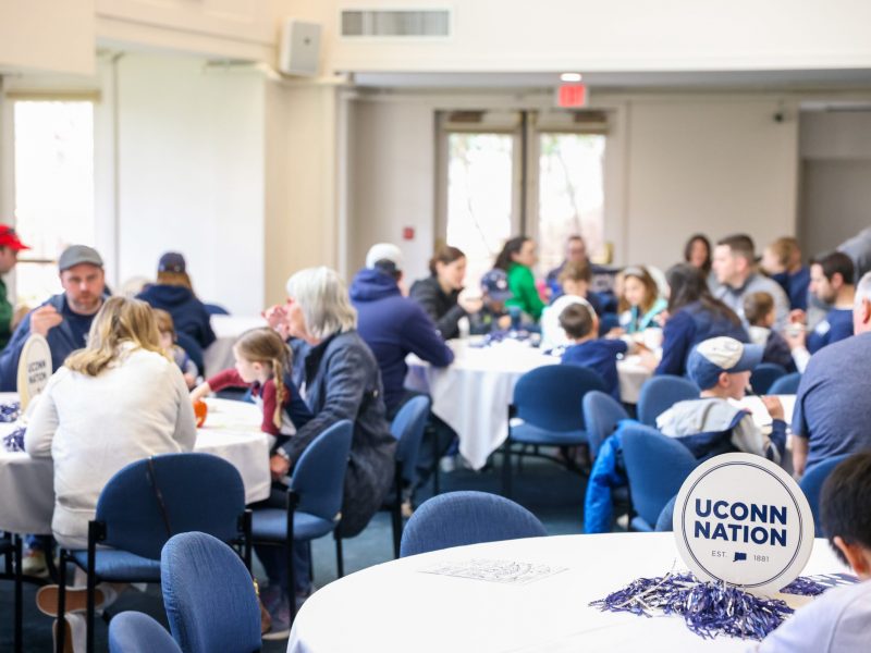 People sitting at tables with a UConn Nation sign in focus
