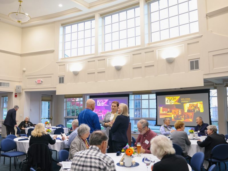 Attendees of the Allen House Jubilee conversing at tables in the Great Hall