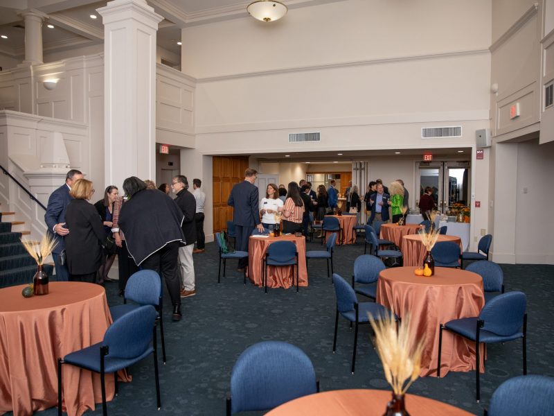 The Great Hall at the Alumni Center decorated for the fall UConn Foundation Board Social featuring copper table cloths and pumpkin and wheat centerpieces