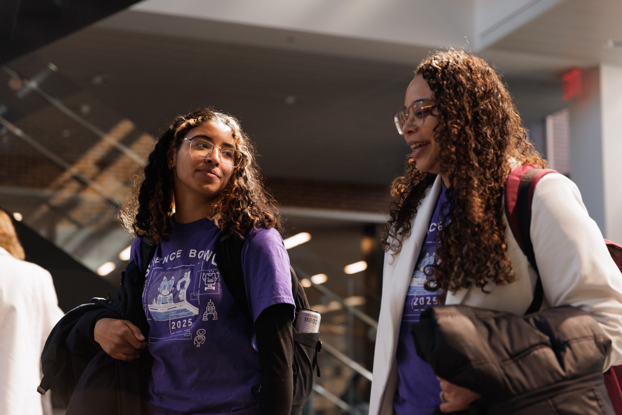 Stephany Santos and a student walk and talk in the halls of an academic building.