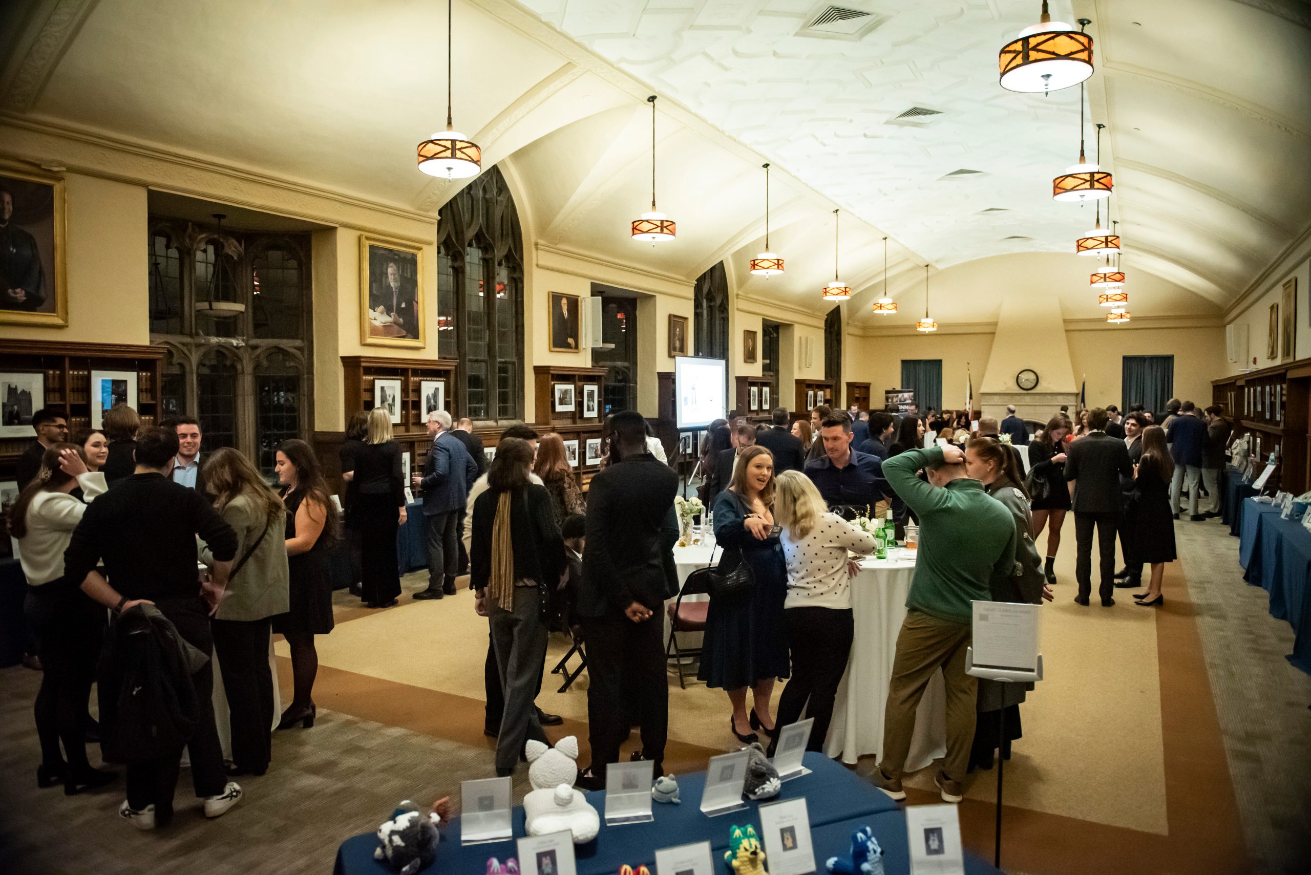 People gathered at various tables engaging in conversation during the PILG auction