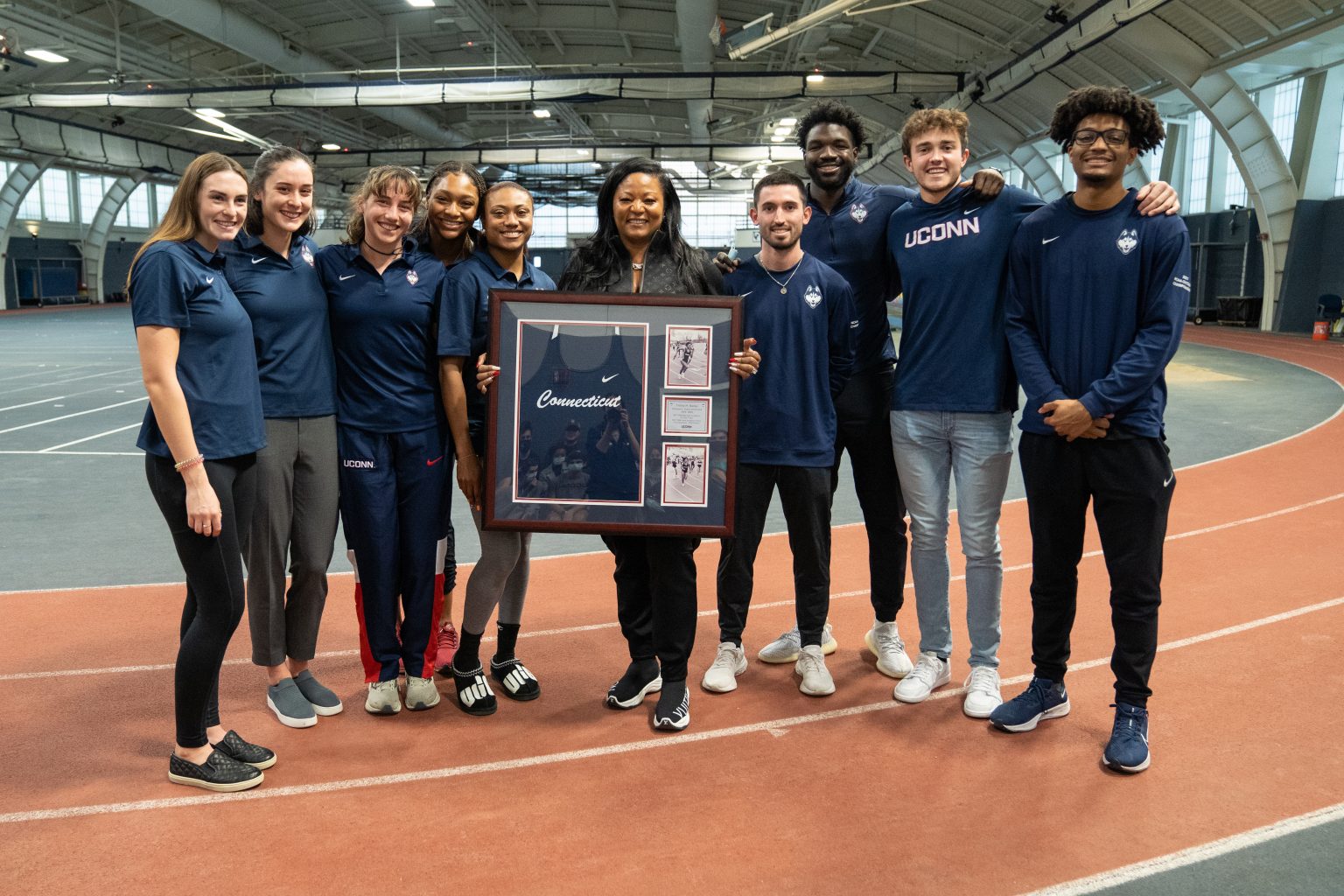 Trisha Bailey pictured with UConn student athletes while she displays her old uniform