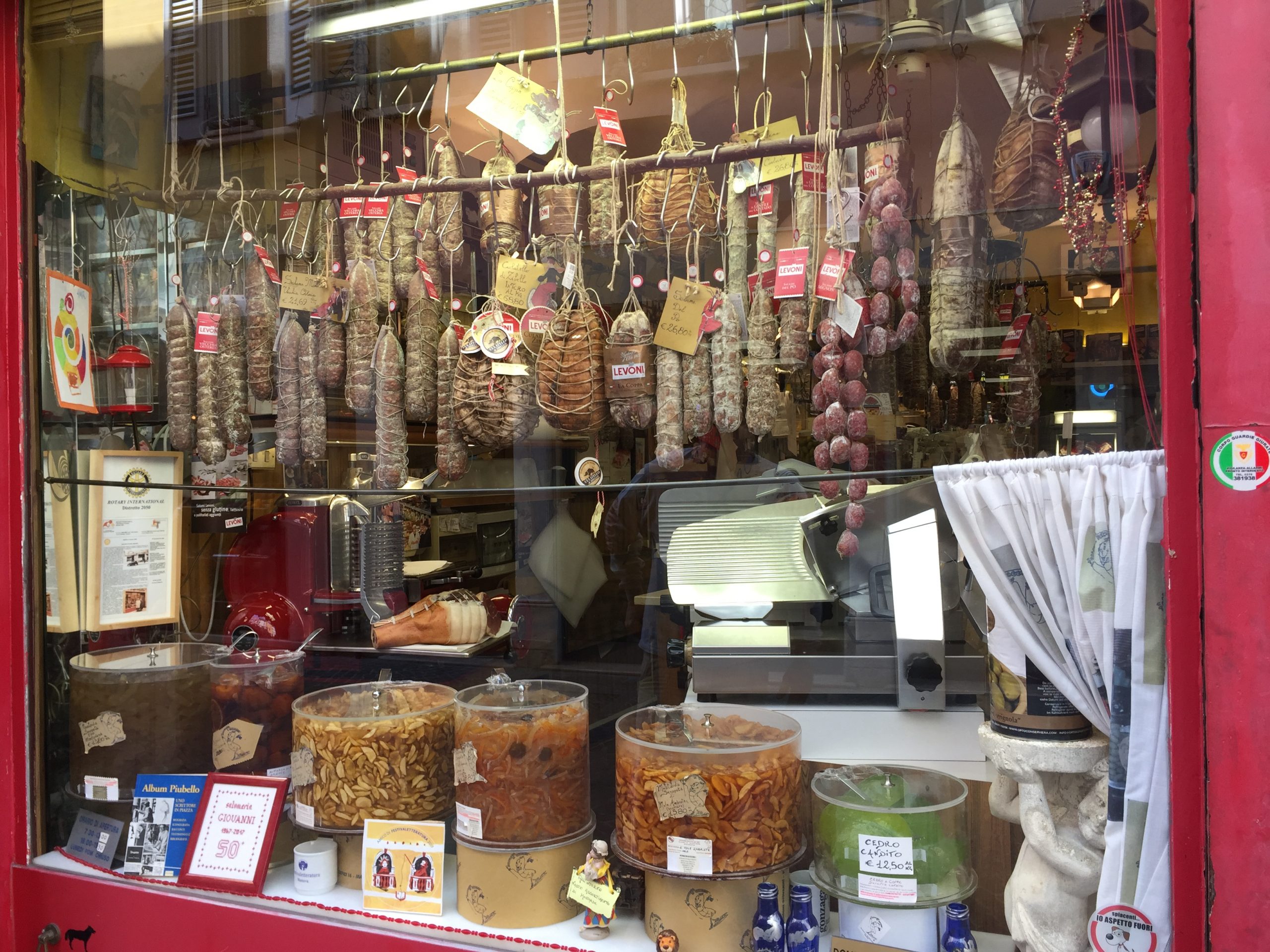 A storefront in northern Italy featuring a variety of Italian meats, herbs, and other artisan goods