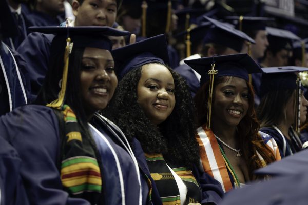 Three girls smiling in their graduation cap and gowns during their graduation ceremony