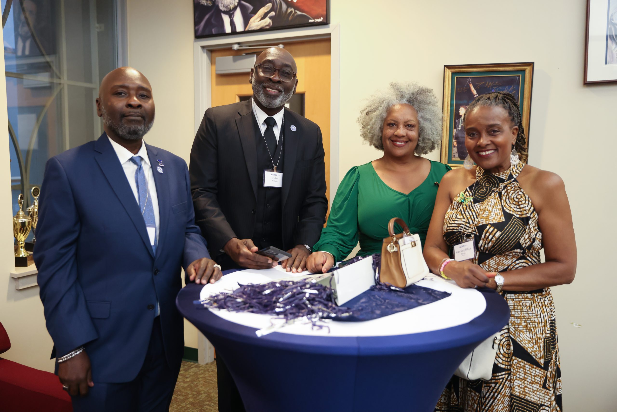 Four people standing at a table and smiling during the Phi Beta Sigma 50th Reunion held at the Student Union