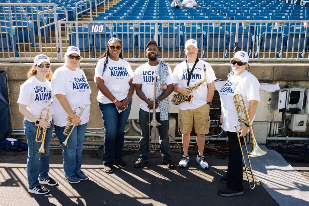 UConn Marching Band alumni posing with their instruments during homecoming