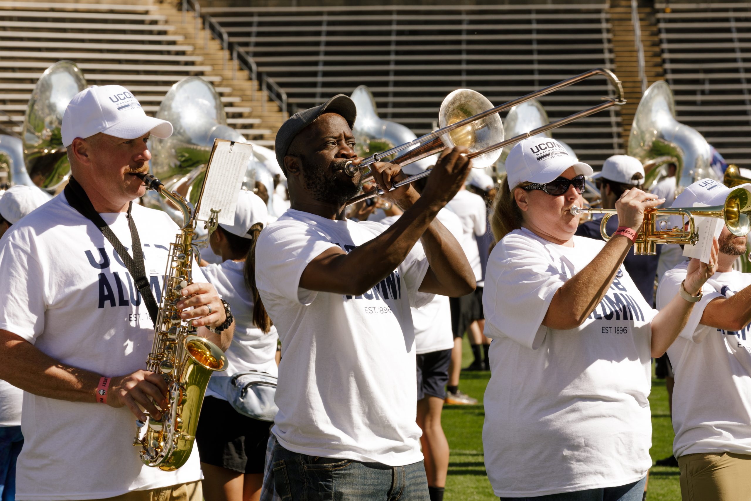UConn Marching Band alumni members playing their instruments on the football team