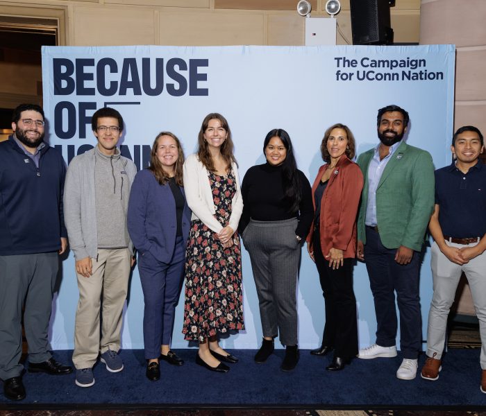Because of UConn NYC The Because of UConn NYC event with attendees standing behind a photo backdrop