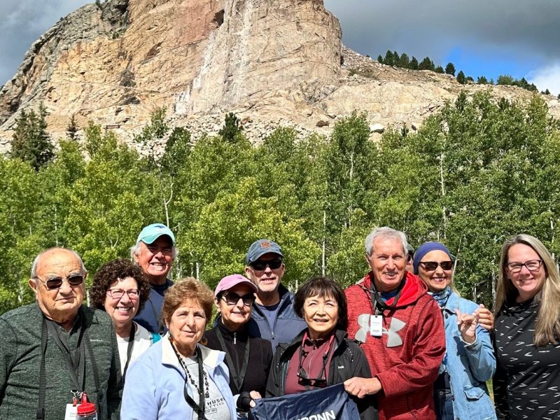 A group of travelers posing behind Mount Rushmore in South Dakota
