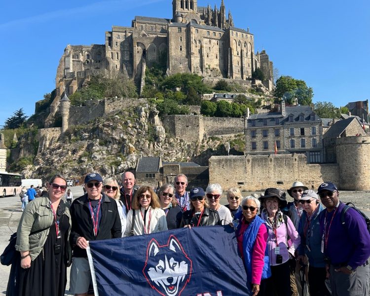 Group Photo_Alumni European coast cruise 2024 Travelers during the alumni European coast cruise posing behind a stone castle