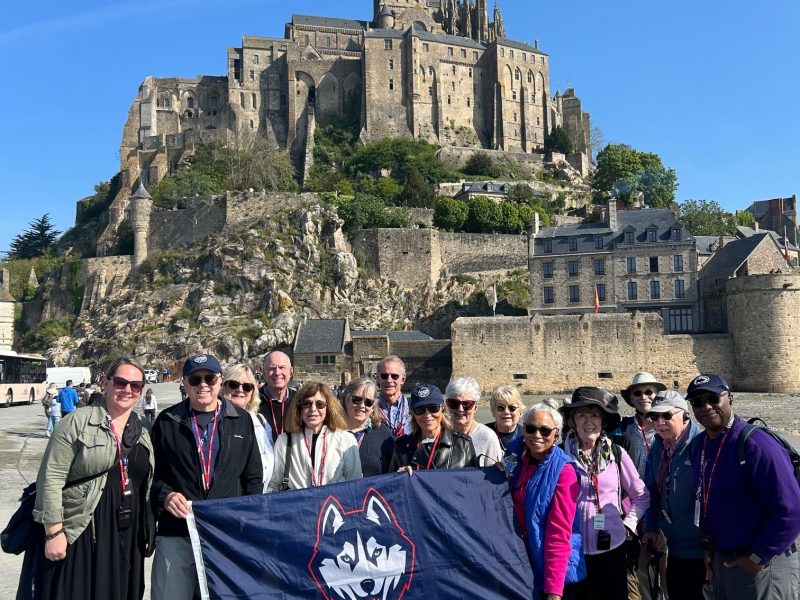 Travelers during the alumni European coast cruise posing behind a stone castle