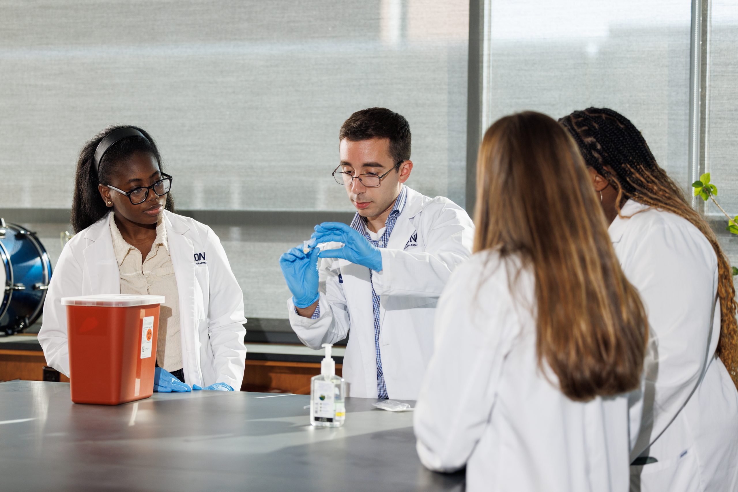 Pharmacy students working in lab together with white lab coats and blue latex gloves