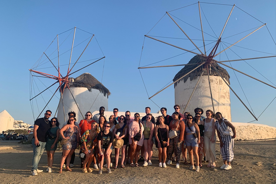 A group of UConn travelers behind two white windmills