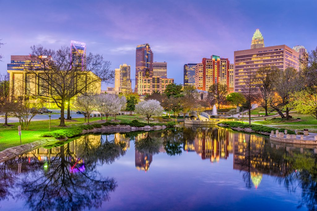 Charlotte city skyline at dusk, viewed from a park with a pond in the foreground