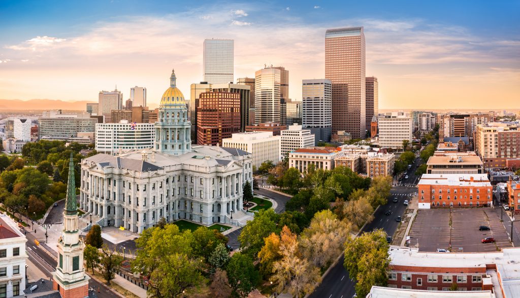 Aerial view of the Denver, Colorado skyline at sunset, with the capitol building in the forefront