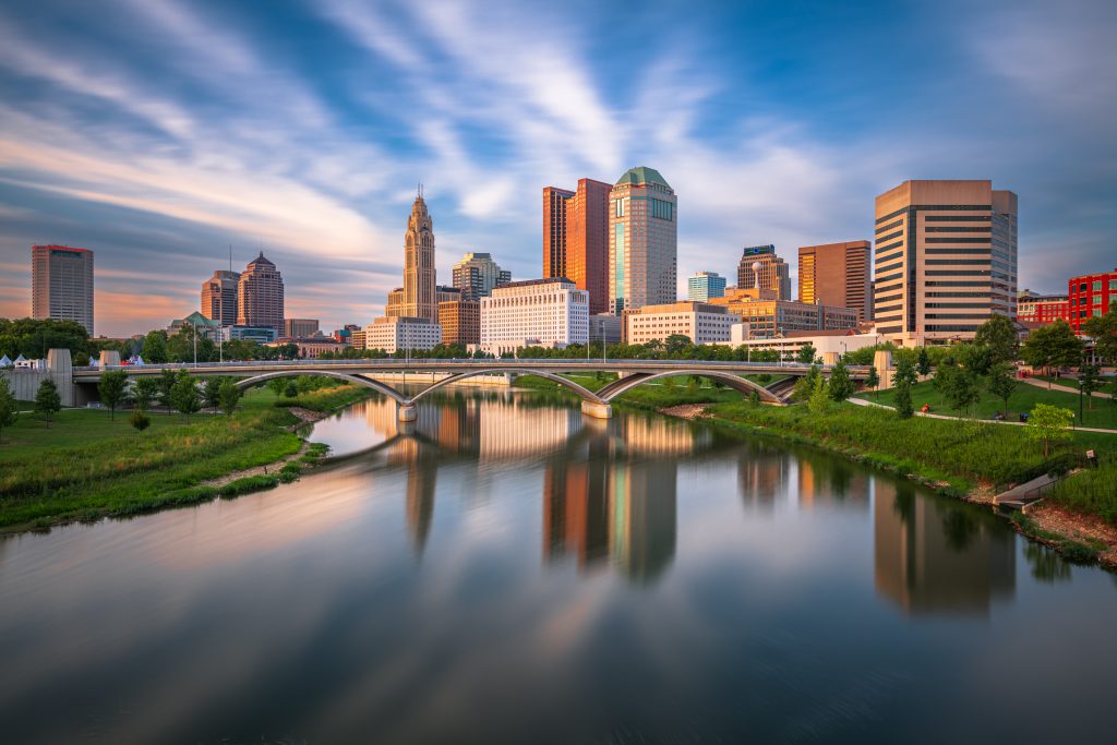 Columbus city skyline on the Scioto River with a blue sky and wispy clouds