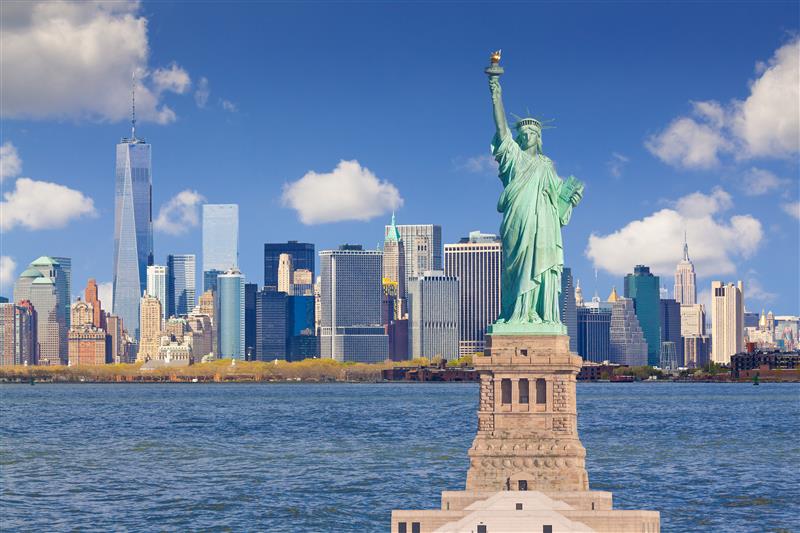 The Statue of Liberty with the New York City skyline in the background during a sunny day