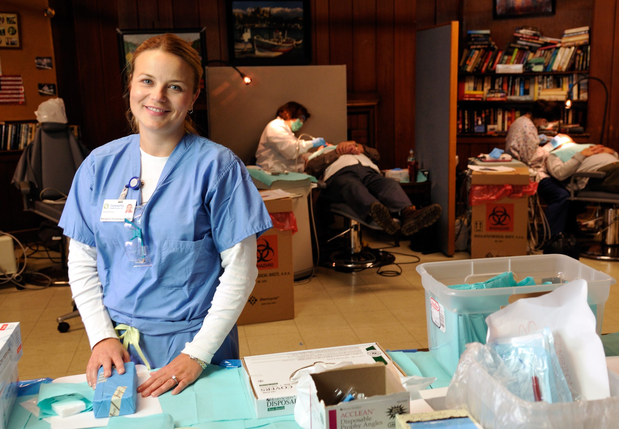 A person in medical scrubs stands at a table organized with dental supplies