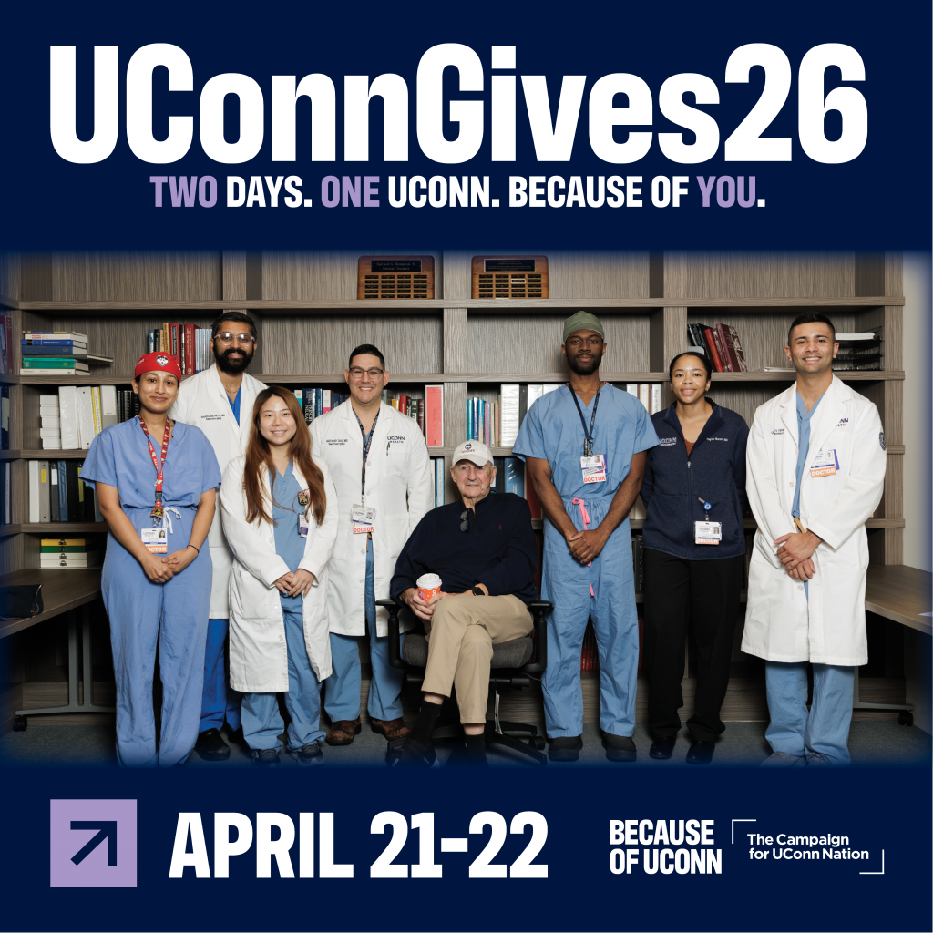 Promotional graphic for UConnGives26 featuring a group of healthcare professionals standing together in front of bookshelves, with one person seated in the center. They are wearing medical scrubs, lab coats, and ID badges. The top of the image reads ‘UConnGives26 – Two Days. One UConn. Because of You.’ The bottom section highlights the event dates ‘April 21–22’ alongside logos for ‘Because of UConn’ and ‘The Campaign for UConn Nation.’