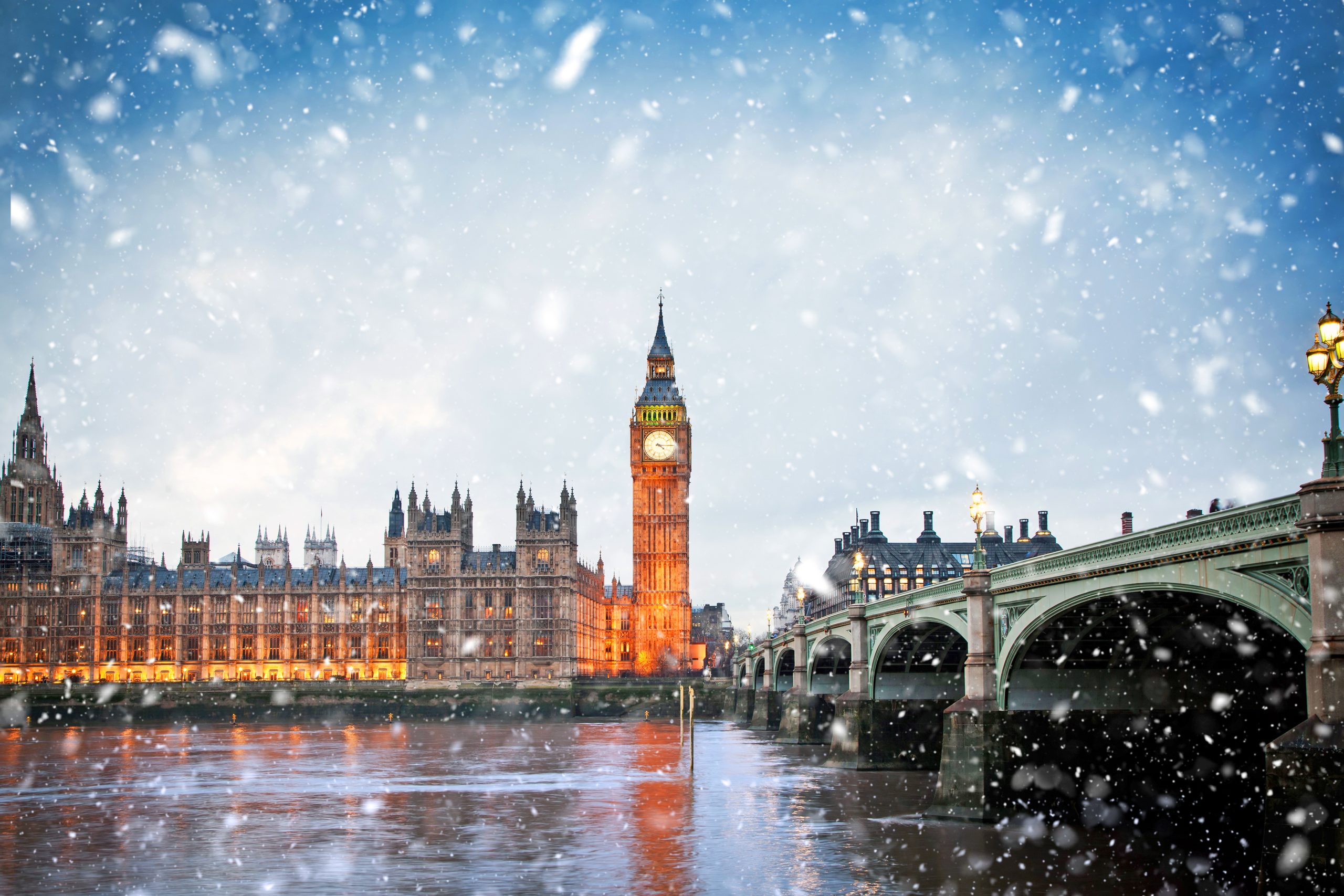 BIg Ben in London, England lit up in the background, with snow flurries in the foreground